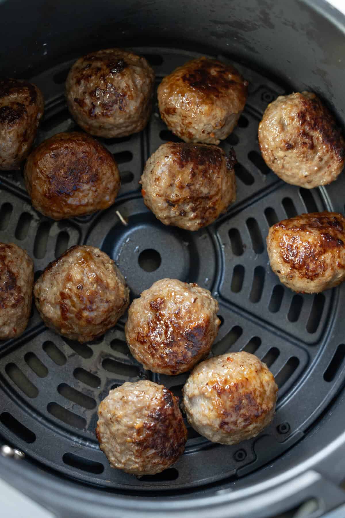 Meatballs cooking in air fryer basket, an easy meatballs recipe perfect for those seeking keto meatballs without breadcrumbs.