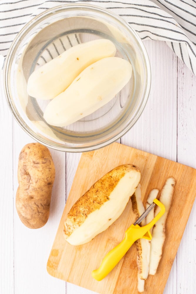 potatoes on a cutting board being peeled