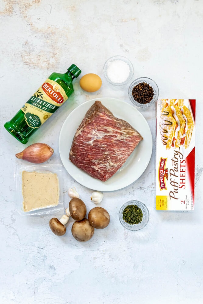 puff pastry, olive oil, beef roast, mushrooms, herbs, spices, pate, lemon, pepper, salt, and pate on a table