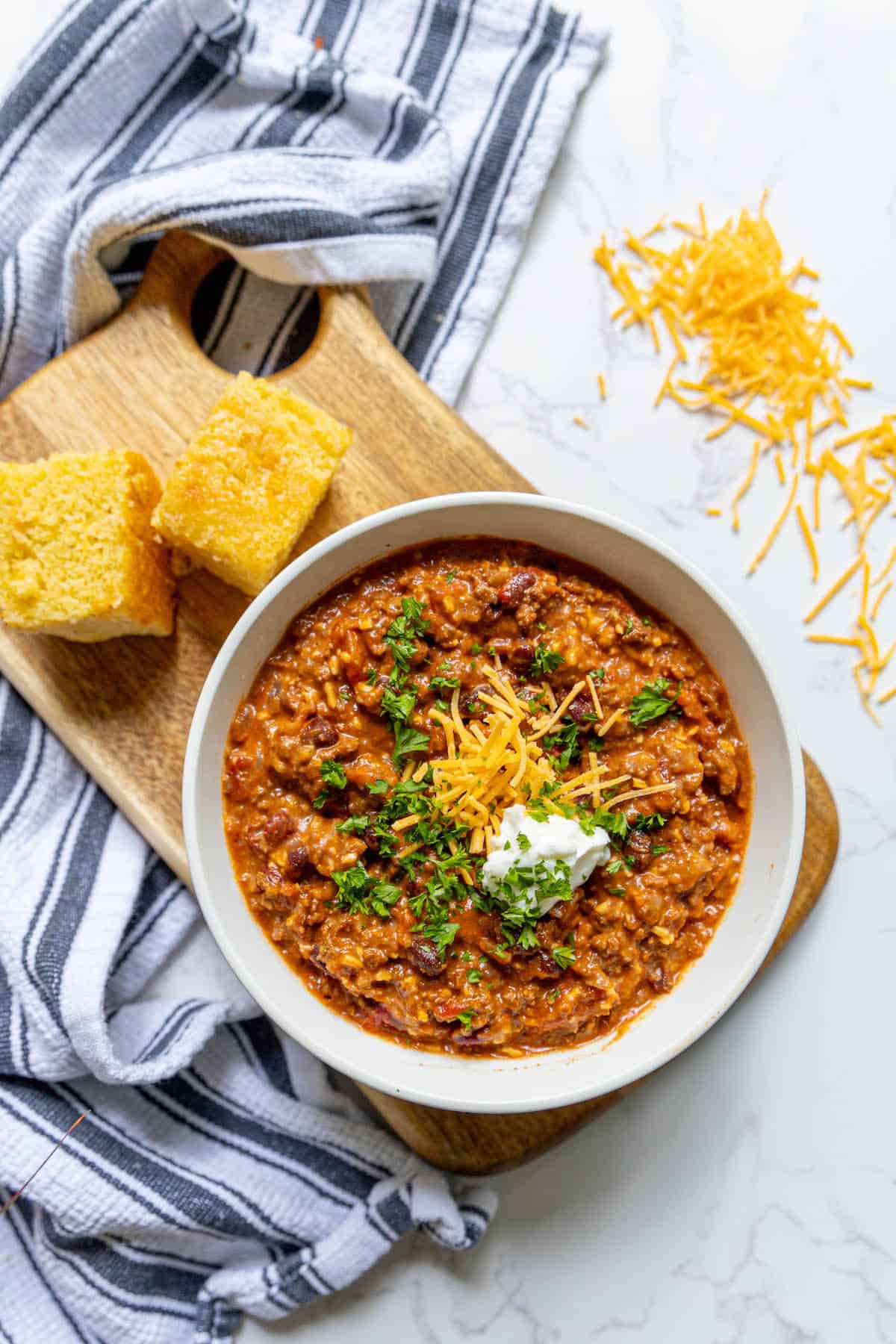 A bowl of chili with sour cream and bread.