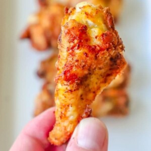 a hand holding a chicken wing seasoned with cajun seasoning