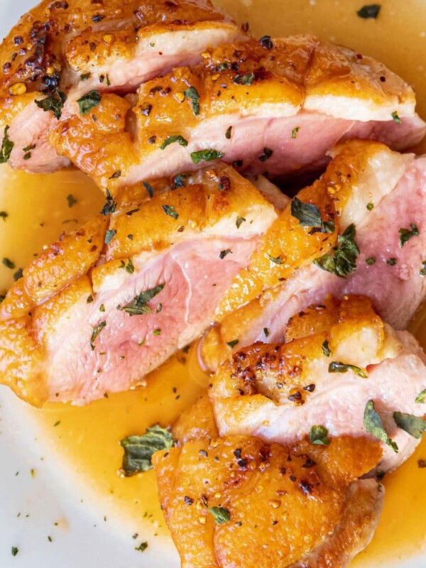 sliced duck breast with crispy skin and orange sauce spooned on top