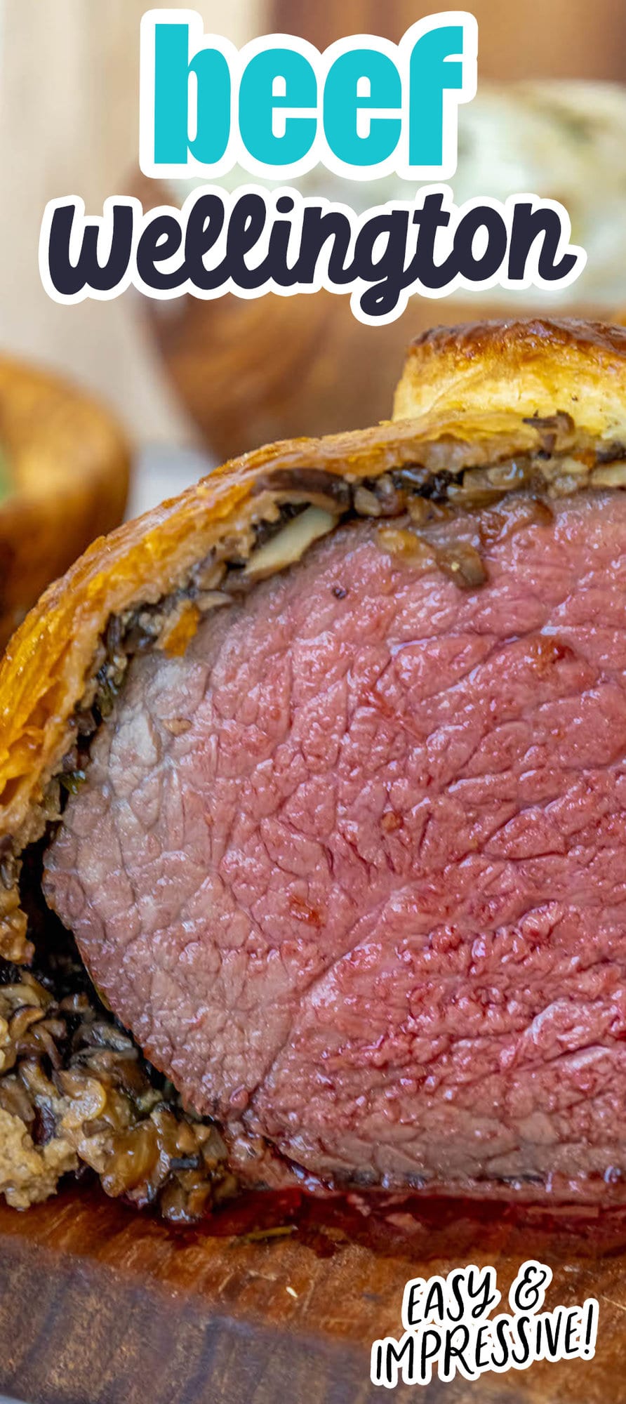 beef wellington wrapped in puff pastry on a cutting board cut in half