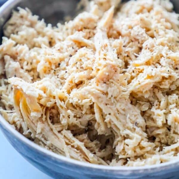 A bowl filled with shredded chicken seasoned with herbs and spices, perfect for an easy boiled chicken recipe.