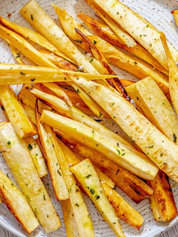 roasted parsnips seasoned with garlic butter and herbs on a white speckled plate