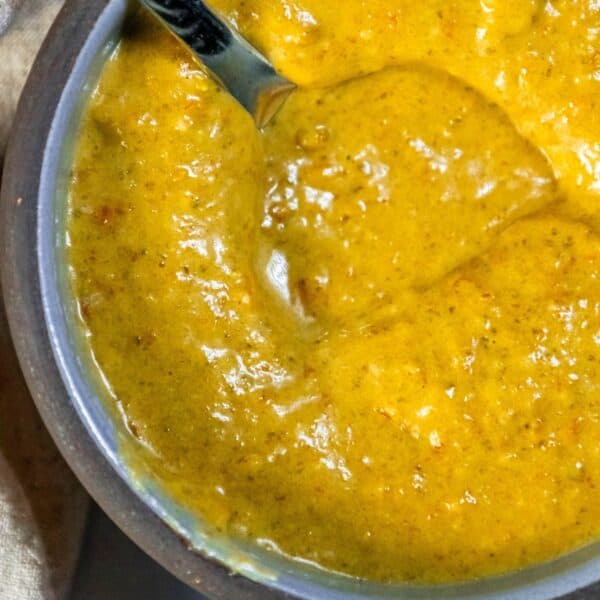 A bowl of soup with a spoon next to it, infused with a hint of spice thanks to the addition of jalapeño.
