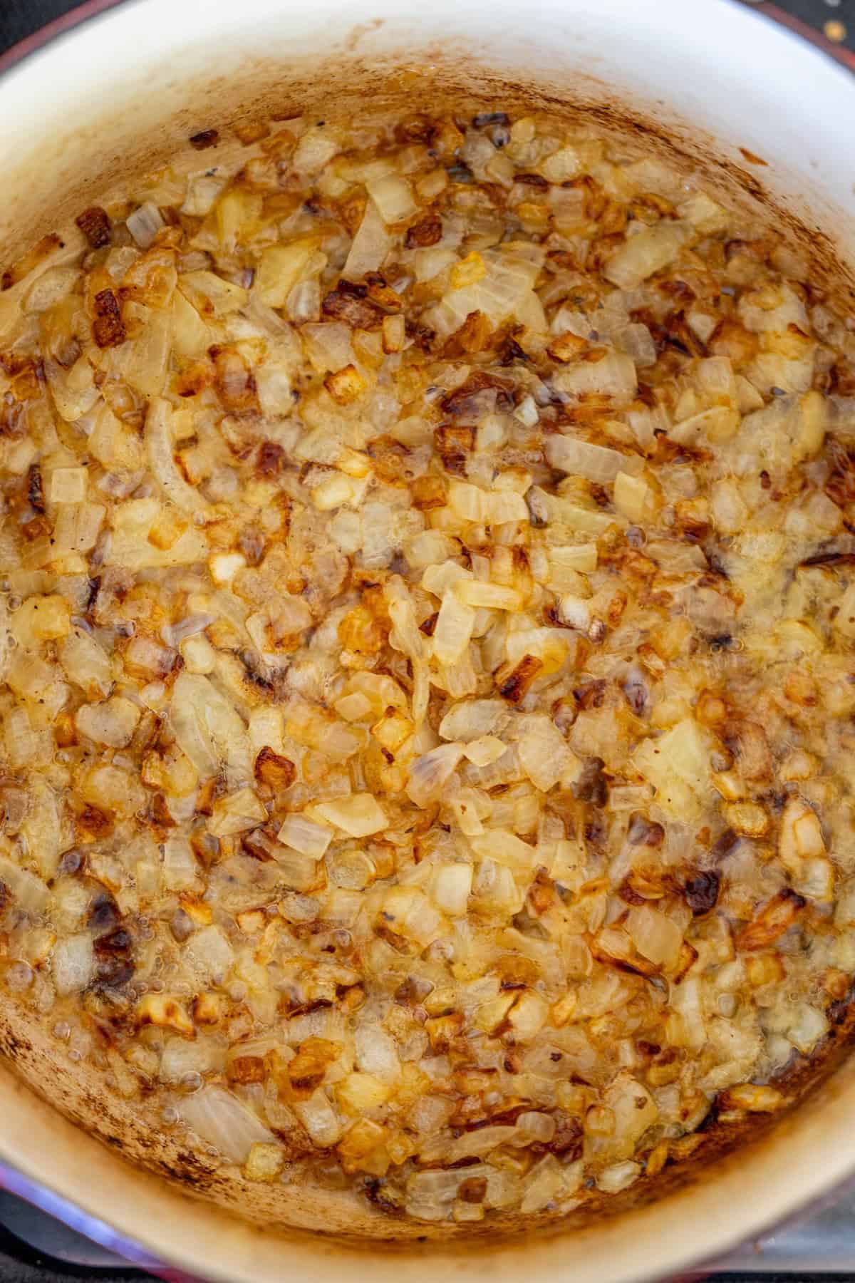 Chopped onions caramelizing in a pot until golden brown set the savory foundation for a creamy hash brown hamburger soup.