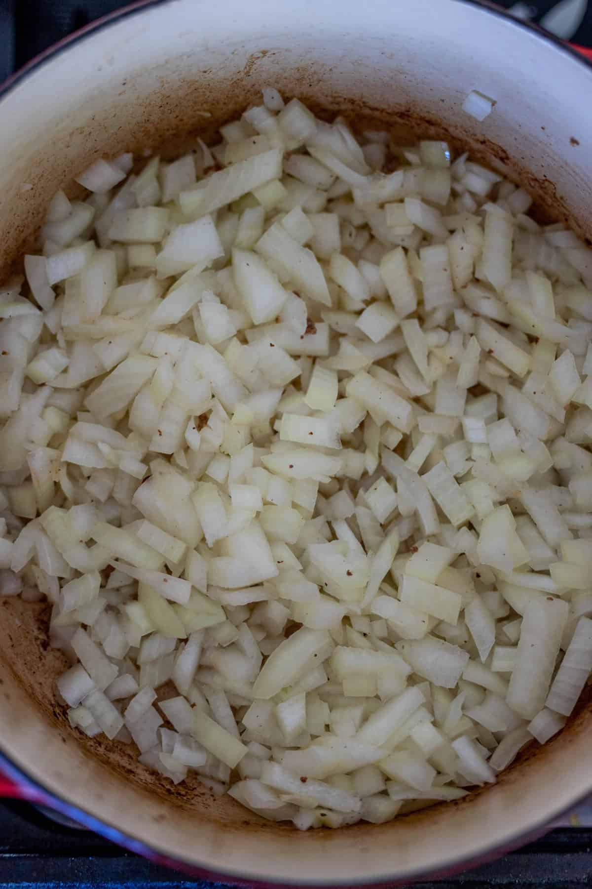 Diced onions sizzle in a large pot, setting the foundation for a creamy hash brown hamburger soup.