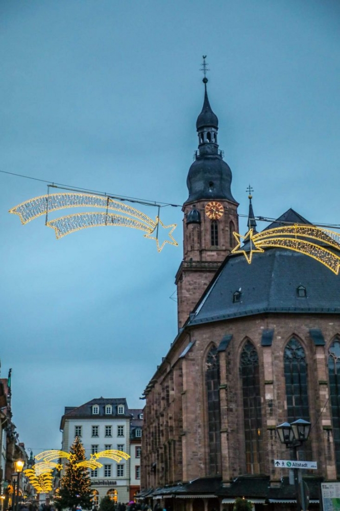 A church with a clock tower in the background during Christmastime in Heidelberg.