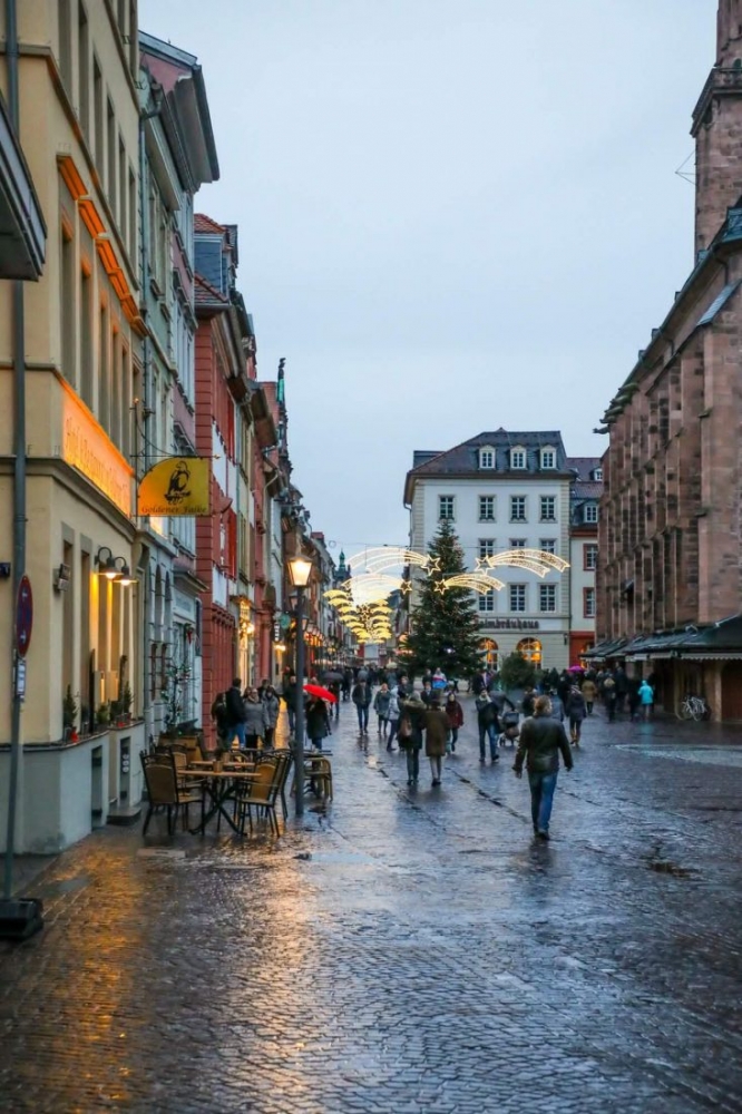 People walking down a cobblestone street in Heidelberg during Christmas.