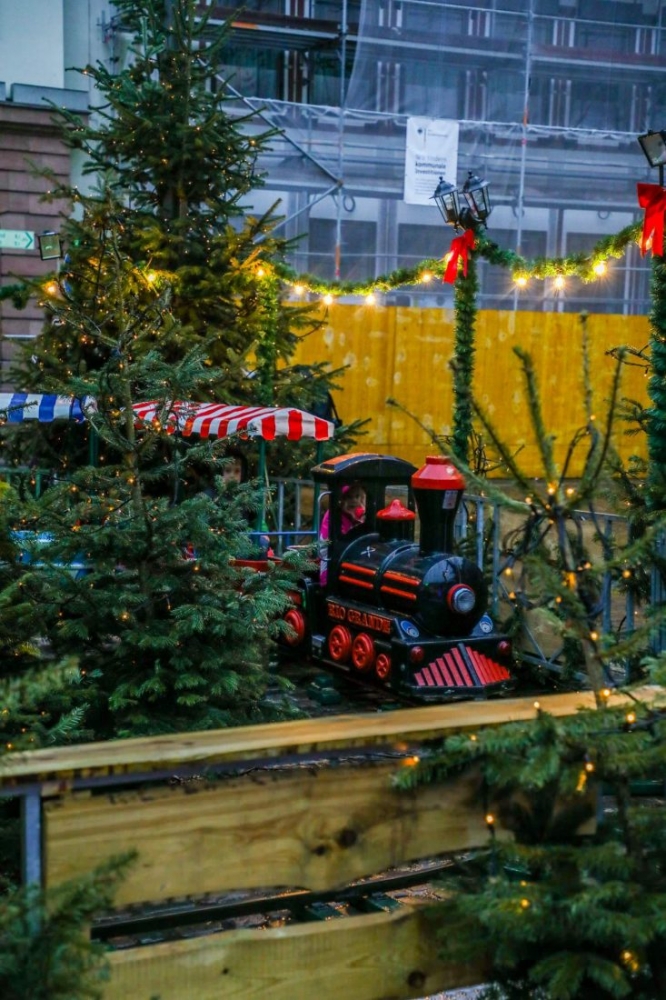 A toy train on a wooden track next to a Christmas tree in Heidelberg at Christmas.
