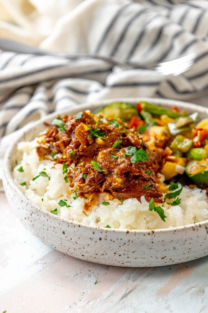 picture of short ribs shredded over rice and topped with cilantro and diced onion