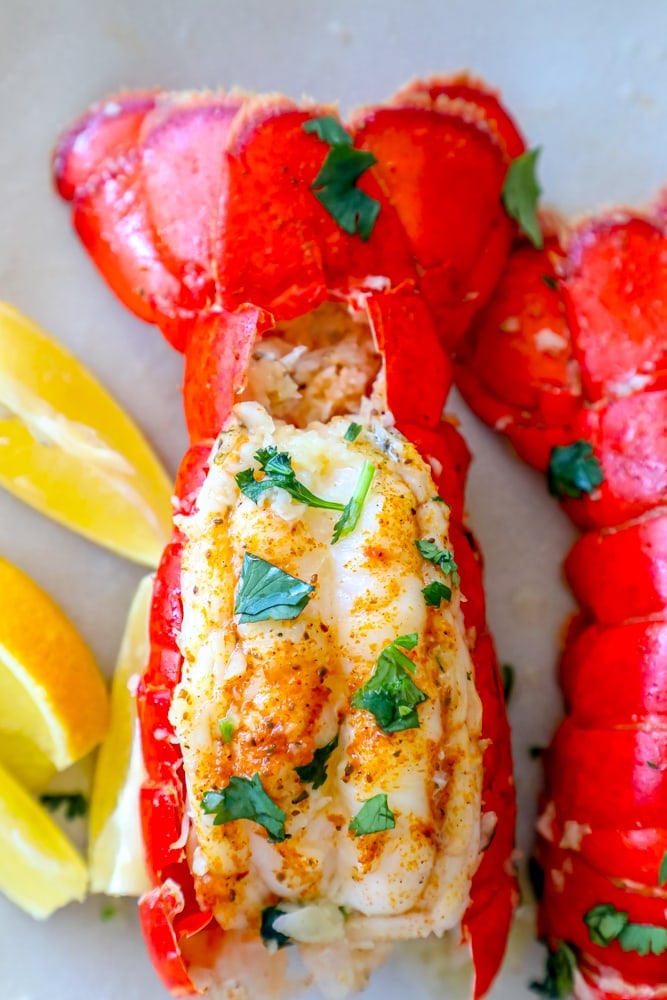 A plate with pressure cooker lobster tails and lemon wedges.