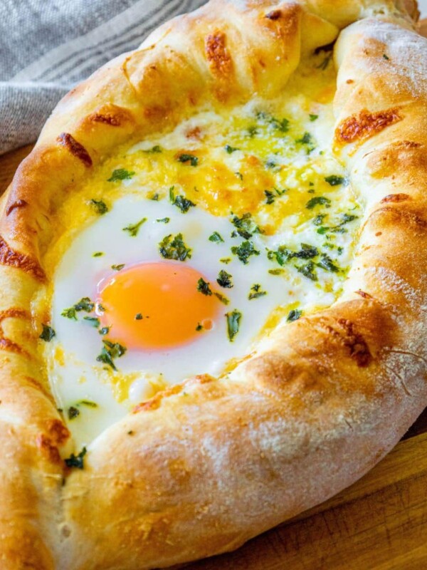 picture of baked khachapuri on a cutting board with egg on top