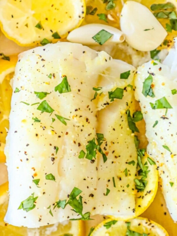 picture of baked cod in a dish with lemon and garlic cloves