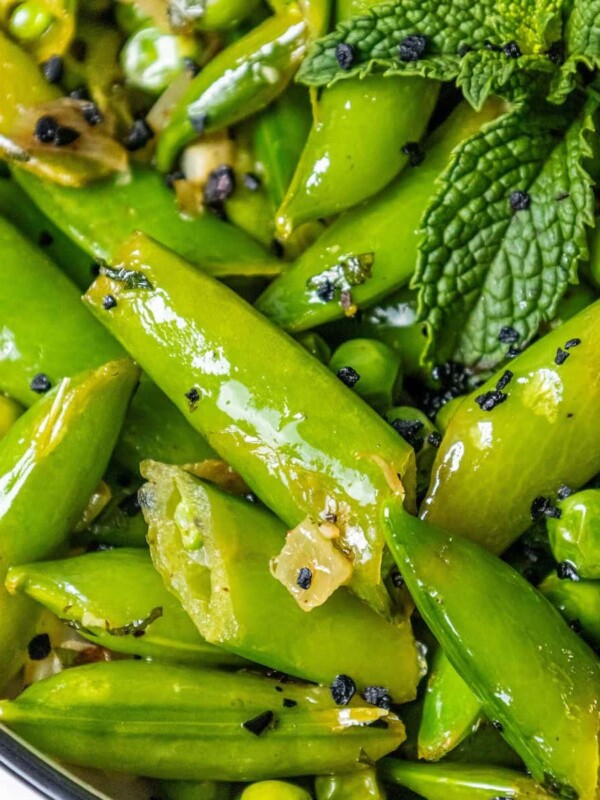 english peas and snap peas sautéed with mint and garlic in a white bowl