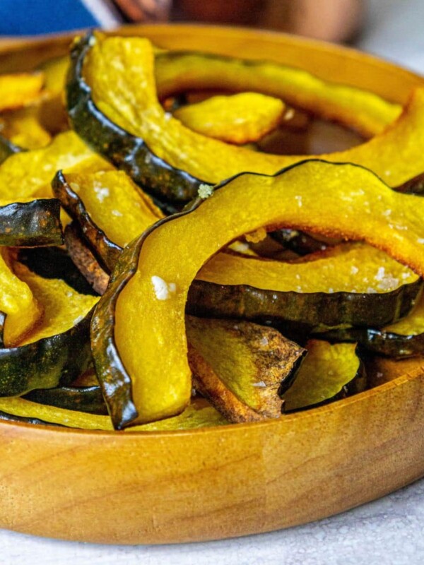 picture of roasted acorn squash slices piled in a wooden bowl seasoned with salt