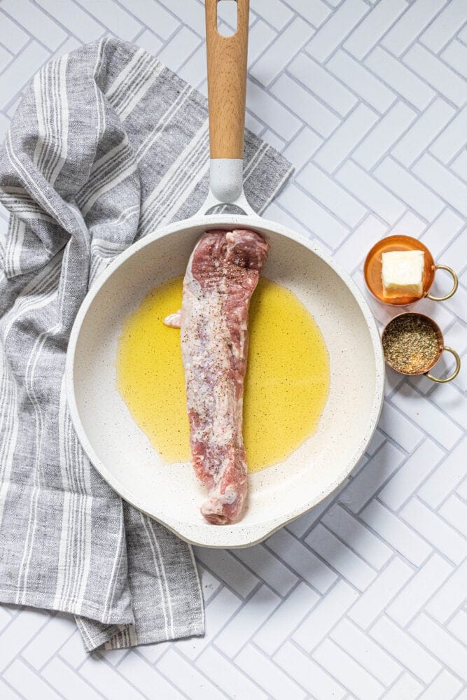 pan with olive oil and raw pork tenderloin in it