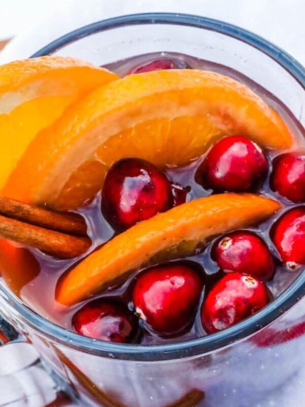 mulled wine in a clear mug with cranberries, cinnamon, and orange slices floating in it