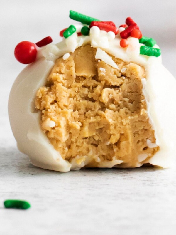 picture of a peanut butter truffle coated in white chocolate on a table with a bite taken out of it